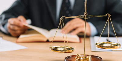 Gold Scales of Justice with man reading book in background