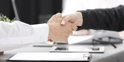 Business man and lady shaking hands over clipboard