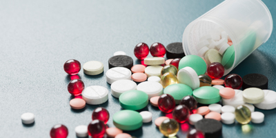 Bottle pouring out various drugs and tablets onto table